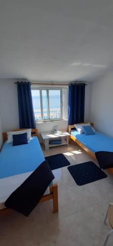 two beds in a room with blue curtains at Vikula in Duće