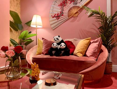 two pandas sitting on a couch in a living room at London Chinatown Apartments in London