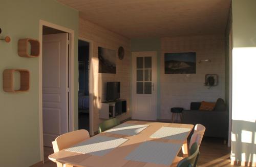 a dining room with a table and chairs in a room at Gîte de la Tuillère, maison contemporaine en bois avec vue et piscine in Saint-Aulaire
