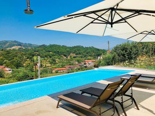 a swimming pool with two chairs and an umbrella at Solar Do Douro in Santa Cruz do Douro