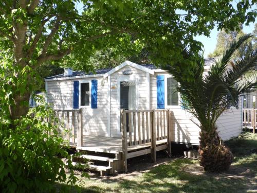 a white tiny house with blue windows and a porch at Village Vacances Les Abricotiers (by Popinns) in Argelès-sur-Mer