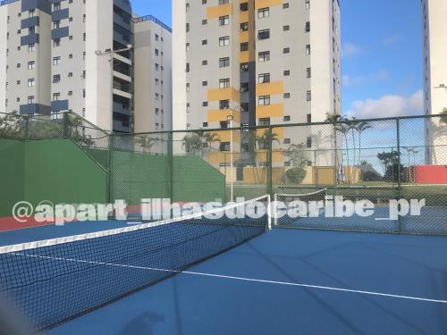 a tennis court with a net and some buildings at Apto Cond Ilhas do Caribe - Pr - Beira Mar in Matinhos