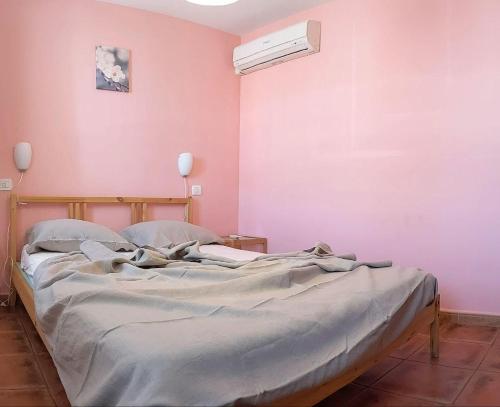 Cama en habitación con pared de color rosa en El Corrillo, en Trevejo