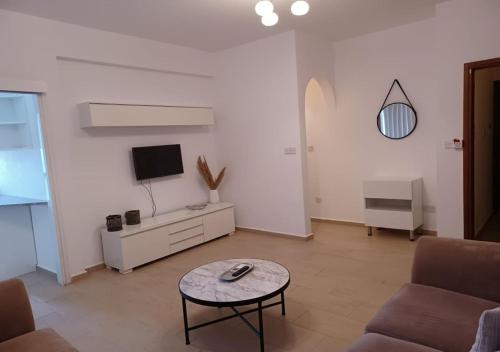 a living room with a couch and a tv and a table at King's Holiday Apartments in Paphos City