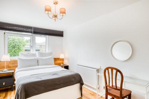 a bedroom with a bed and a mirror and a chair at Homely 4 Bedroom House in Brixton in London