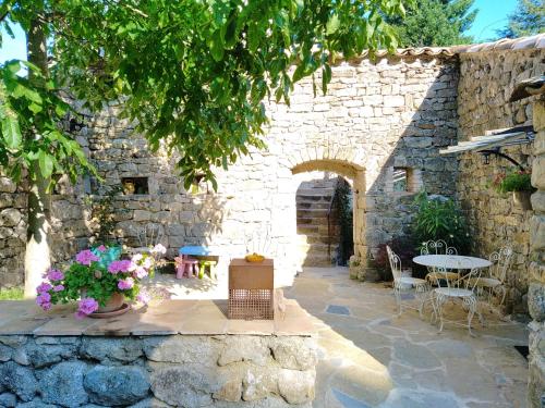 a stone building with a table and chairs and flowers at Les MIMOSAS Gîte du Mas Haut in Saint-Jean-du-Gard