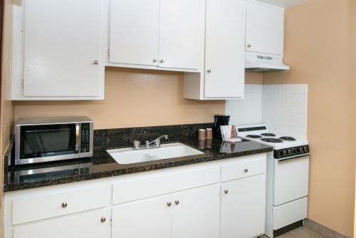a kitchen with a stove top oven and a microwave at Dana Point Marina Inn in Dana Point