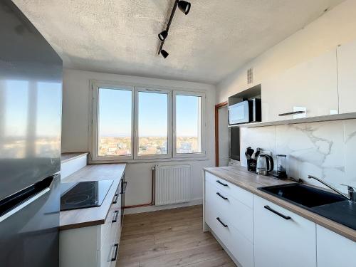 une cuisine avec des placards blancs et une grande fenêtre dans l'établissement Agréable appartement 4 pièces, vue Mont Ventoux, proche remparts, à Avignon