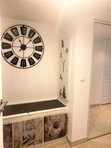 une grande horloge sur un mur avec un banc dans l'établissement T2 proche de la gare, à 10 minutes à pieds de la Croisette, piscine & parking dans résidence de haut standing, à Cannes