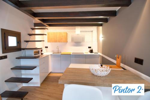 a kitchen with white cabinets and a wooden table at Cuencaloft el mirador del pintor in Cuenca
