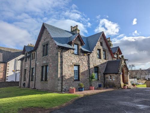una grande casa in pietra con tetto nero di Cambeth Lodge a Inverness