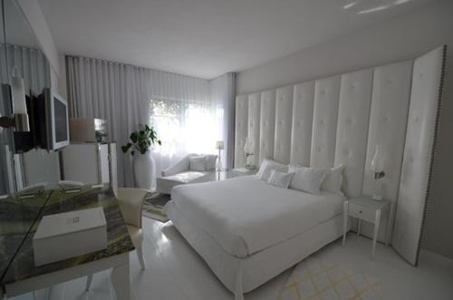 a white bedroom with a large bed and a table at Sea Mountain Nude Resort & Spa Hotel - Adults Only in Desert Hot Springs