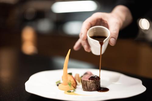 a person pouring chocolate sauce onto a plate of food at SPA & Naturhotel Outside in Matrei in Osttirol