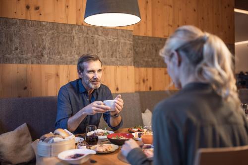 a man sitting at a table looking at his cell phone at SPA & Naturhotel Outside in Matrei in Osttirol
