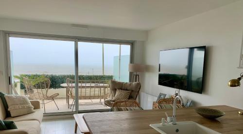 a living room with a table and chairs and a balcony at Vue Magnifique Face Mer in La Baule