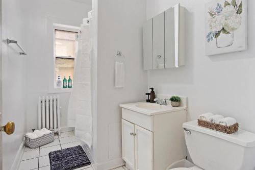 a white bathroom with a toilet and a sink at Stay in Style Expansive 2BR Unit with Balcony - Buckingham 3 in Chicago