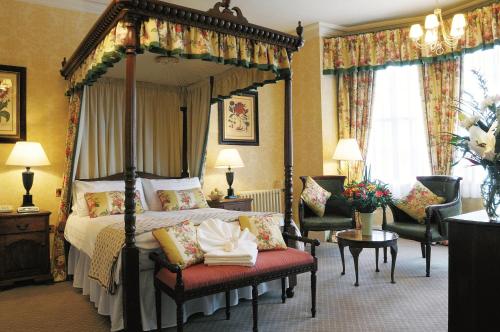 a bedroom with a four poster bed and two chairs at The Bear Hotel in Devizes