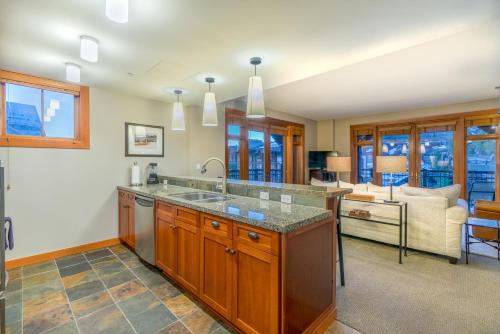 a kitchen with a sink and a living room at Capitol Peak Lodge by Snowmass Mountain Lodging in Snowmass Village