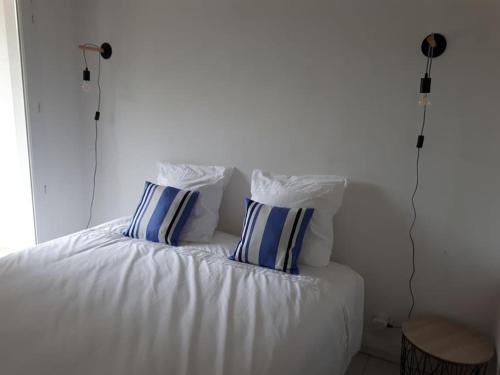 un lit blanc avec des oreillers bleus et blancs dessus dans l'établissement Plage d'Erretegia et Bidart à pied, à Bidart