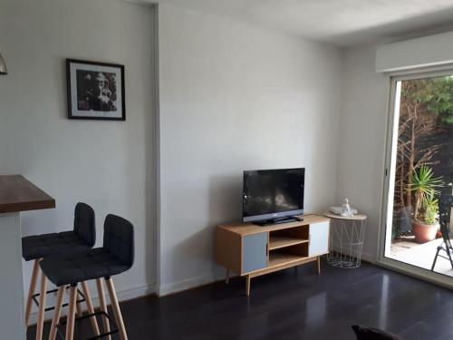 - un salon avec une télévision et deux chaises dans l'établissement Plage d'Erretegia et Bidart à pied, à Bidart