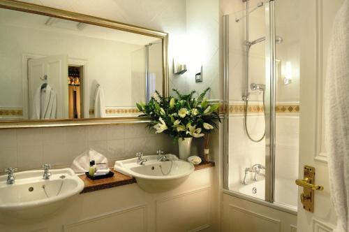 a bathroom with two sinks and a mirror and a shower at The Bear Hotel in Devizes