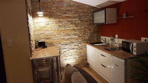 a kitchen with a counter and a brick wall at Cosy Love & Spa Love room avec spa, hammam et sauna privatif in Cemboing