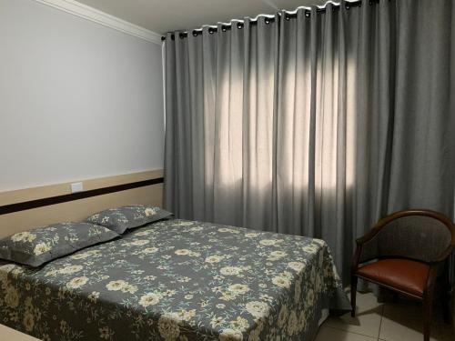 a bedroom with a bed and a curtain and a chair at Aguas da Serra 322 A in Rio Quente