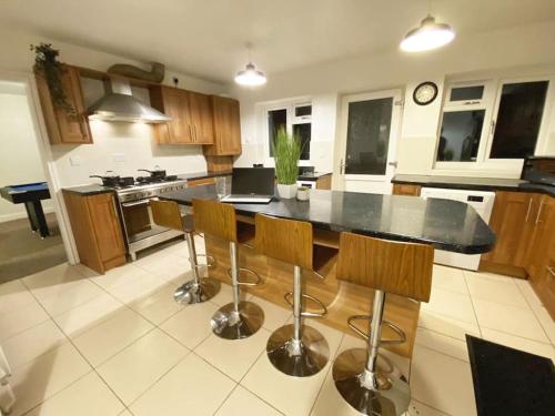 a kitchen with a black counter and wooden cabinets at Team House -Walsall, M6 J7 - 11 beds, Nr B-Ham, Free Parking in Bescot