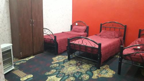two beds in a room with red walls at WadiRum Village Lodge in Wadi Rum