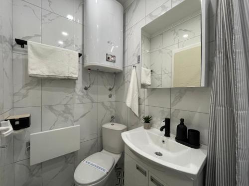 a white bathroom with a toilet and a sink at Apartments TEMA in Sombor