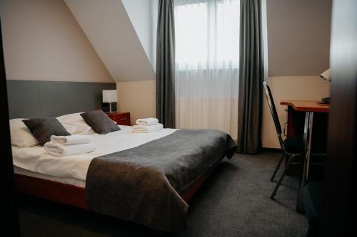 Hotel Resident في Nowa Sarzyna: غرفة نوم بسرير ومكتب ونافذة