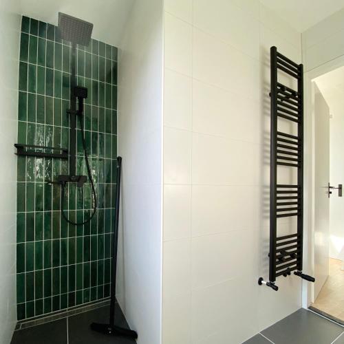 a bathroom with a shower with green tiles at Huisje Hygge - luxe bungalow met grote tuin in Ewijk