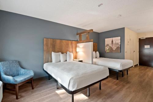 a hotel room with two beds and a chair at Extended Stay America Suites - Fort Lauderdale - Plantation in Plantation
