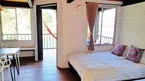 a bed in a room with windows and a table at Ecolodge Bahia del Peñón in Guatapé