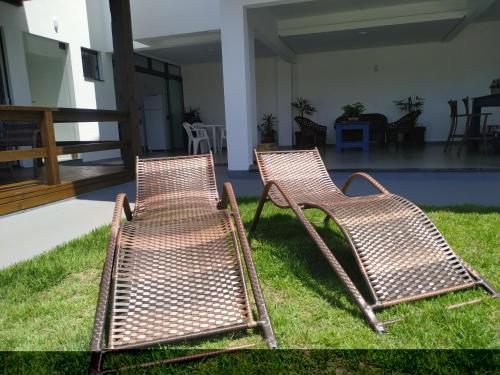 two chairs sitting on the grass in a yard at Bella Ciao Hospedaria in Passo de Torres