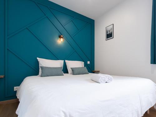 Un dormitorio con una gran cama blanca con una pared azul. en Aventures modernes, en Roanne
