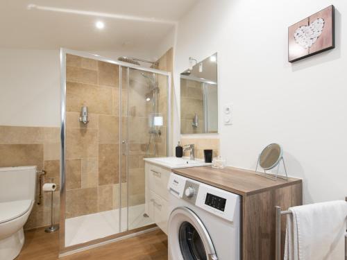 een wasmachine in een badkamer met een douche bij Aventures modernes in Roanne