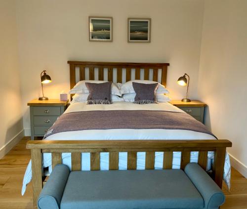 a bedroom with a large bed with a blue bench at The Heronry Hideaway with luxury hot tub in Ballachulish