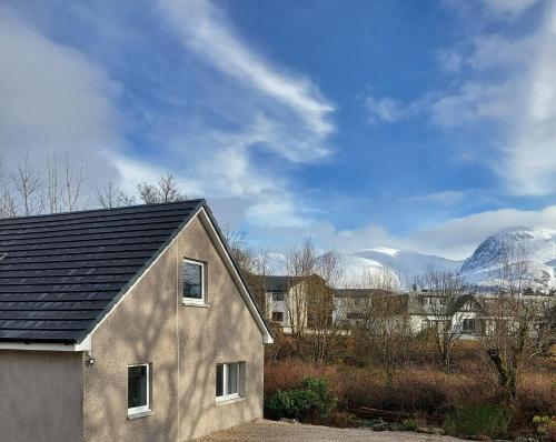 a house with a roof with mountains in the background at Taorbeag at Taormina in Fort William
