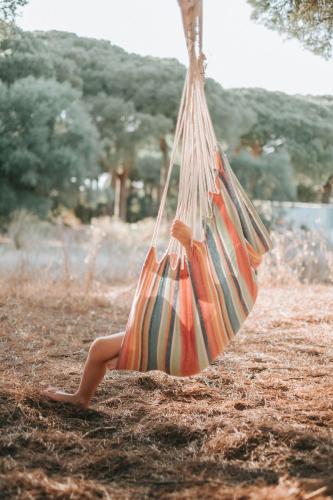 a person sitting in a hammock in a field at miCielo - Baumhäuser in Vejer de la Frontera