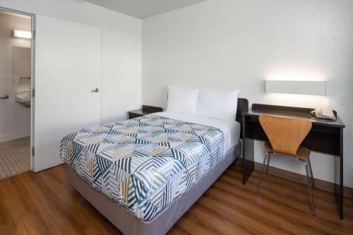 a bedroom with a bed and a desk and a chair at Motel 6-Santa Barbara, CA - State Street in Santa Barbara