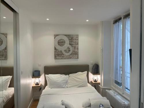 une chambre avec un lit avec des draps blancs et une fenêtre dans l'établissement Paris Cosy Apartment Opéra Vendome Galeries Lafayette, à Paris