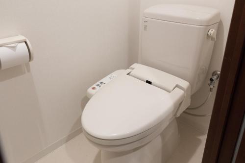 een badkamer met een wit toilet met deksel naar beneden bij Hotel Hakata Place in Fukuoka