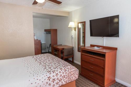 a hotel room with a bed and a flat screen tv at Esquire Inn in Elko