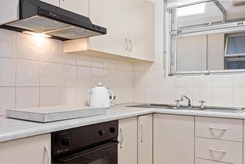 a white kitchen with a sink and a stove at Taft Apartments in Adelaide