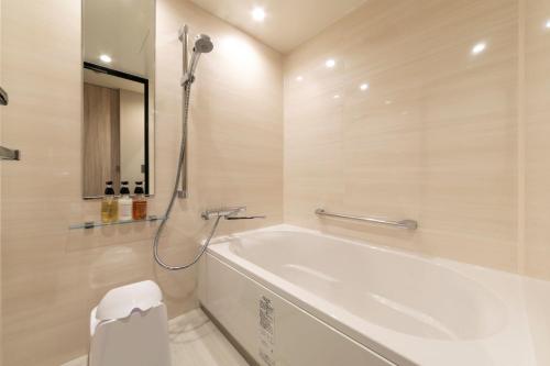 een witte badkamer met een bad en een douche bij S-Peria Hotel Fukuoka Nakasu in Fukuoka