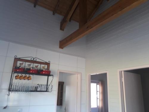 a kitchen with white walls and a shelf with pots and pans at Pousada Cabanas Flor de Mel in Urubici