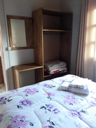a bedroom with a bed with purple flowers on it at Pousada Cabanas Flor de Mel in Urubici