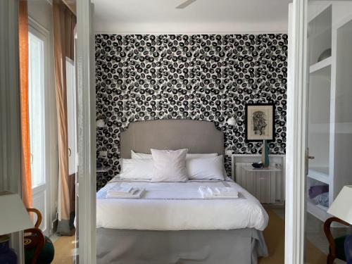 una camera da letto con un letto e carta da parati in bianco e nero di Les Lilas a Roquebrune-Cap-Martin