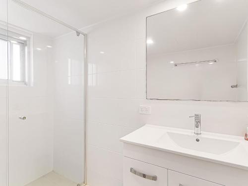 ein weißes Badezimmer mit einem Waschbecken und einem Spiegel in der Unterkunft Rainbow Pacific Unit 15 in Gold Coast